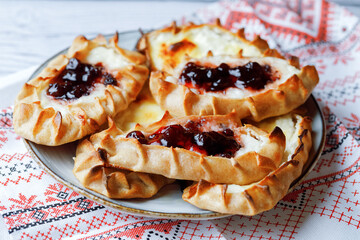 Karelian plays or Karjalanpiirakka. Traditional finnish or north russian pastry with cottage cheese and jam on clay plate.