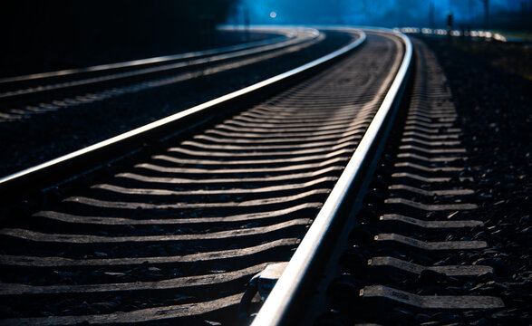 Two parallel curved railway Tracks on an unelectrified main railroad line between Hagen and Arnsberg in Sauerland Germany. Blue hour twilight atmosphere with reflecting rails, blurred background.