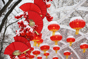 Chinese New Year decorations in winter city. Festive alley decorated with red paper fans and lanterns