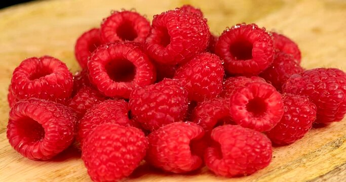 Close up video of fresh and wet raspberries on a rotating wooden plate. They contain plenty of minerals, especially phosphorus, calcium, magnesium and iron