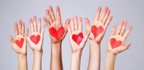 People raising hands with red hearts painted

