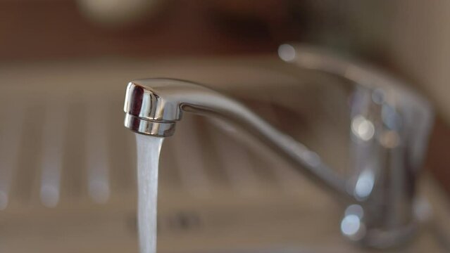 Close up locked down shot of a man turning the faucet off in the kitchen and the water stops running from the outlet