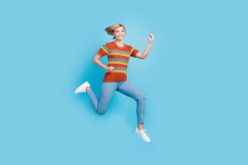 Full size photo of overjoyed satisfied woman dressed knit t-shirt denim trousers run to empty space isolated on blue color background