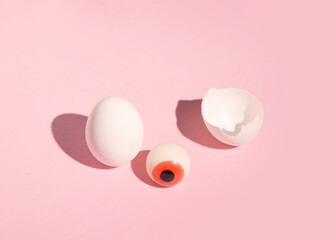 A candy in the shape of an eyeball falls out of an eggshell. Creative Halloween layout.