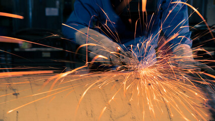 Grinding machine in action with bright sparks in construction factory.