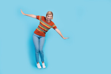 Full size photo of impressed careless woman dressed knit t-shirt denim pants look down at empty space isolated on blue color background