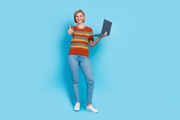 Full length photo of satisfied girl wear strited t-shirt holding laptop show you thumb up good work isolated on blue color background