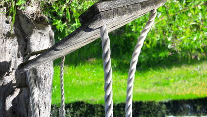 Old rusty wooden swing on the grass
