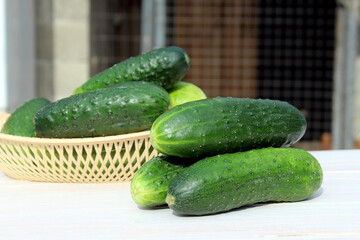 There are cucumbers in a basket on a wooden table.