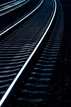 Two parallel curved railway Tracks on an unelectrified main railroad line between Hagen and Arnsberg in Sauerland Germany. Blue hour twilight atmosphere with reflecting rails, blurred background.