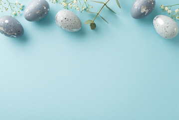 Easter concept design: top view image capturing slate greyish eggs, surrounded by gypsophila, and eucalyptus, organized on pastel blue background, leaving portion open for text or promotional material