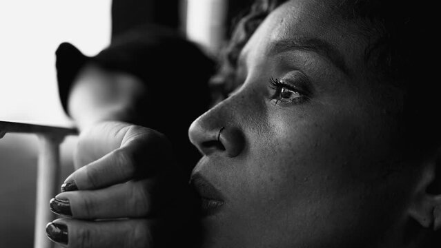 One depressed lonely 50s African American woman with sorrow emotion regretting past events feeling quiet despair alone in solitude captured in dramatic monochrome, black and white