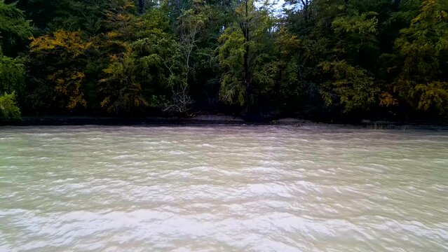 R&uuml;ckw&auml;rts Kamerafahrt aus dichtem Wald an Fluss und sanften Wellen unter einem bew&ouml;lkten Himmel. Drohnenaufnahme, Graasten, D&auml;nemark
