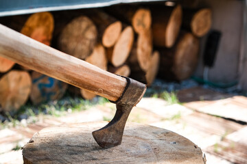 axe on stack of firewood chunk pine log firewood stashed for cold winter ready for fire place or...