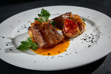 Close-up of beef tongue with roasted potatoes on a white plate