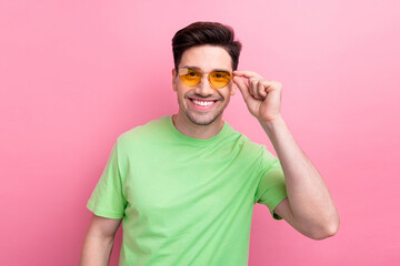 Photo portrait of young macho nice guy wear green t shirt brunet hair boyfriend touching sunglasses isolated on pink color background