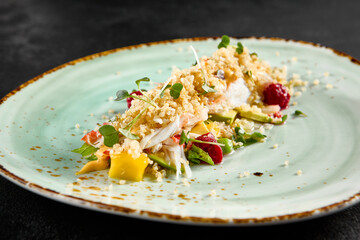 Elegant salad with avocado, crab, and quinoa, artfully arranged on a speckled turquoise plate