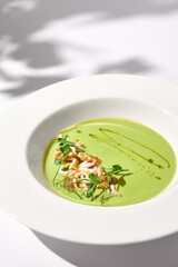 Spinach Cream Soup with Calamari Topping, Artfully Presented on a White Plate with Shadow, Perfect for Gourmet Food Advertising