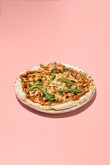 Gluten-free pizza with mushrooms and tomatoes on a stylish plate with a pink backdrop