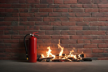 Fire extinguisher and bonfire on brick wall background.