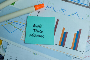 Concept of Avoid These Mistakes write on sticky notes isolated on Wooden Table.