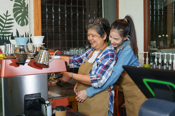 The owner cafe single mother businessman gray haired pensioner making coffee behind coffee maker counter Surrounded coffee making equipmentdaughter hugs happy mother behind coffee shop small business