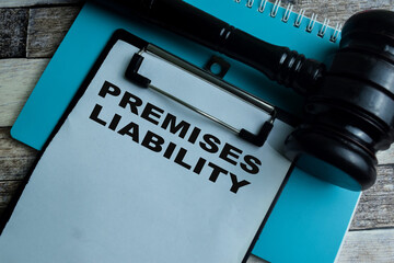 Concept of Premises Liability write on paperwork with gavel isolated on wooden background.