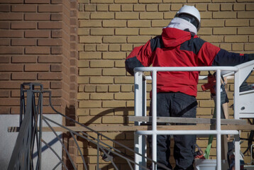 construction worker mason in cherry picker restoring brick wall