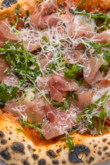Pizza with prosciutto, arugula and parmesan