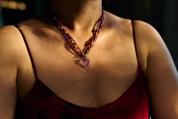 Close-up shot of a middle-aged woman's neck. Necklace with a heart-shaped pendant from rose quartz...