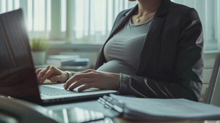 pregnant woman in a professional setting, working on a laptop.