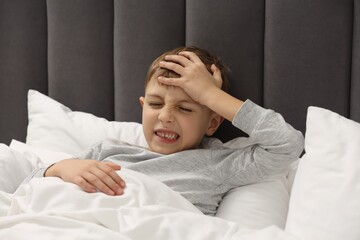 Little boy suffering from headache in bed at home © New Africa