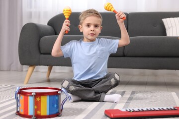 Little boy playing toy maracas at home