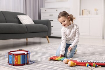 Little girl playing toy xylophone at home
