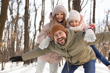Happy family spending time together in snowy forest. Space for text