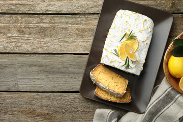 Tasty lemon cake with glaze and citrus fruits on wooden table, flat lay. Space for text
