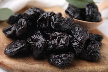 Tasty dried prunes on wooden board, closeup