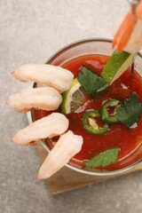 Tasty shrimp cocktail with sauce, parsley and lime in glass on light grey table, top view