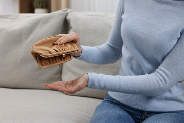 Woman with empty wallet on sofa indoors, closeup