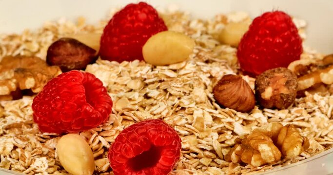 Close up video of a natural, healthy und very delicious muesli with nuts and red raspberries