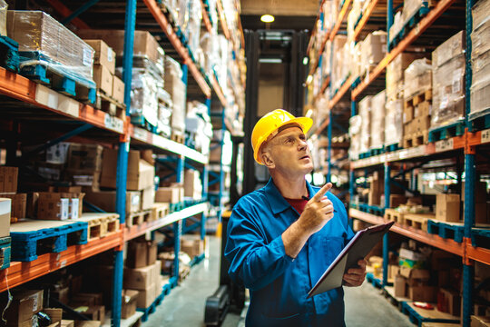 Male warehouse manager inspecting inventory with clipboard