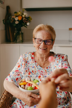 Elderly woman smiling while receiving a fruit bowl