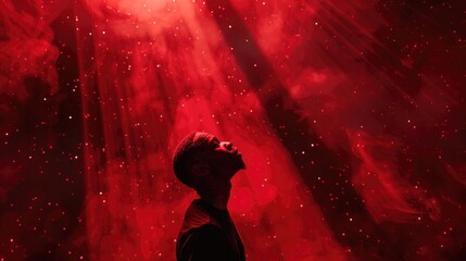 Portrait of a young man praying against a background of red smoke. Worship.