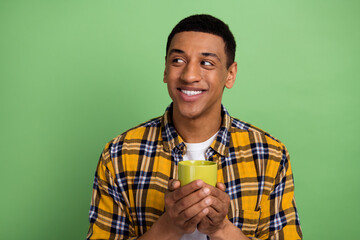 Photo of young guy wear plaid yellow shirt holding cappuccino mug looking empty space when colleagues envy him over green color background - obrazy, fototapety, plakaty