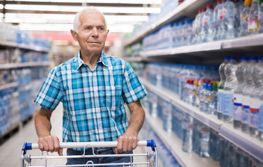 Old age man choosing bottle of drinking water in supermarket
