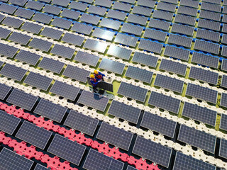 Top aerial of Photovoltaic engineers work on floating photovoltaics. workers Inspect and repair the solar panel equipment floating on water. Engineer working setup Floating solar panels on lake.