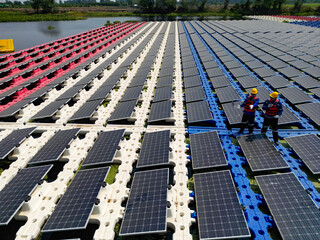 Top aerial of Photovoltaic engineers work on floating photovoltaics. workers Inspect and repair the solar panel equipment floating on water. Engineer working setup Floating solar panels on lake.