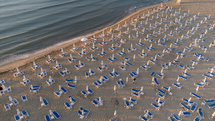 aerial view of beach with umbrellas down, sand and sea waves landscape.