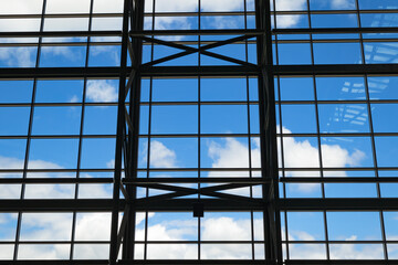 Abstract architectural blue sky and white clouds behind steel beams and supports. 