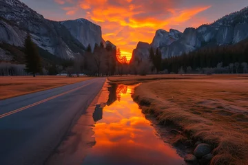 Photo sur Plexiglas Réflexion A road leading to a sunrise that envelopes the mountains in a warm, amber light, with a nearby creek reflecting the sunrise's glow.